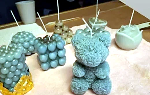 Candele fatte a mano su un tavolo: cubi a bolle, orsetto di rose e altre forme